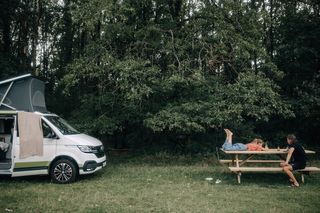 Kind mit Vater neben ihrem Camper auf Campingplatz im Wald