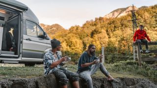3 Männer, die vor einem Grand California sitzend ihr Essen genießen